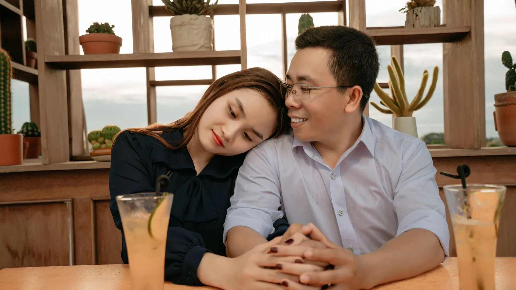 An Asian couple holding hands during an intentional café date.