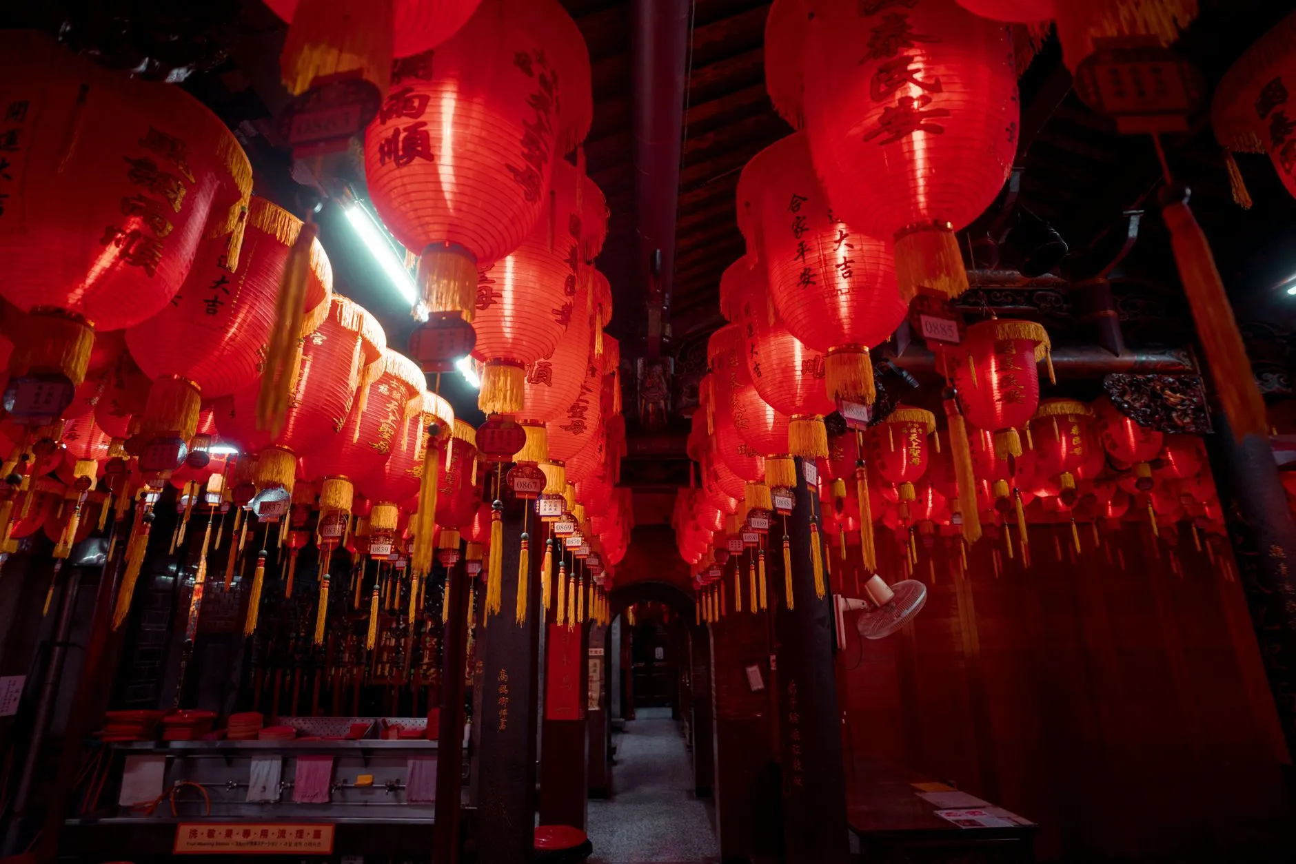 Red Chinese lanterns hanging in rows in a traditional indoor space.