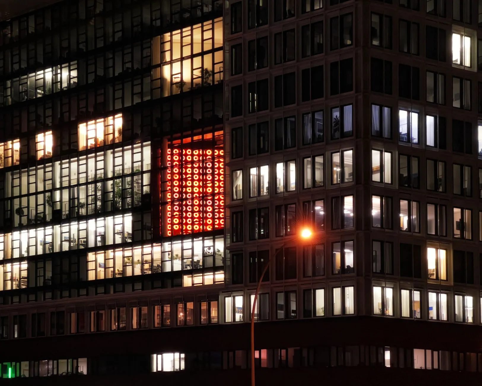 An office building at night with lit windows above a city street.