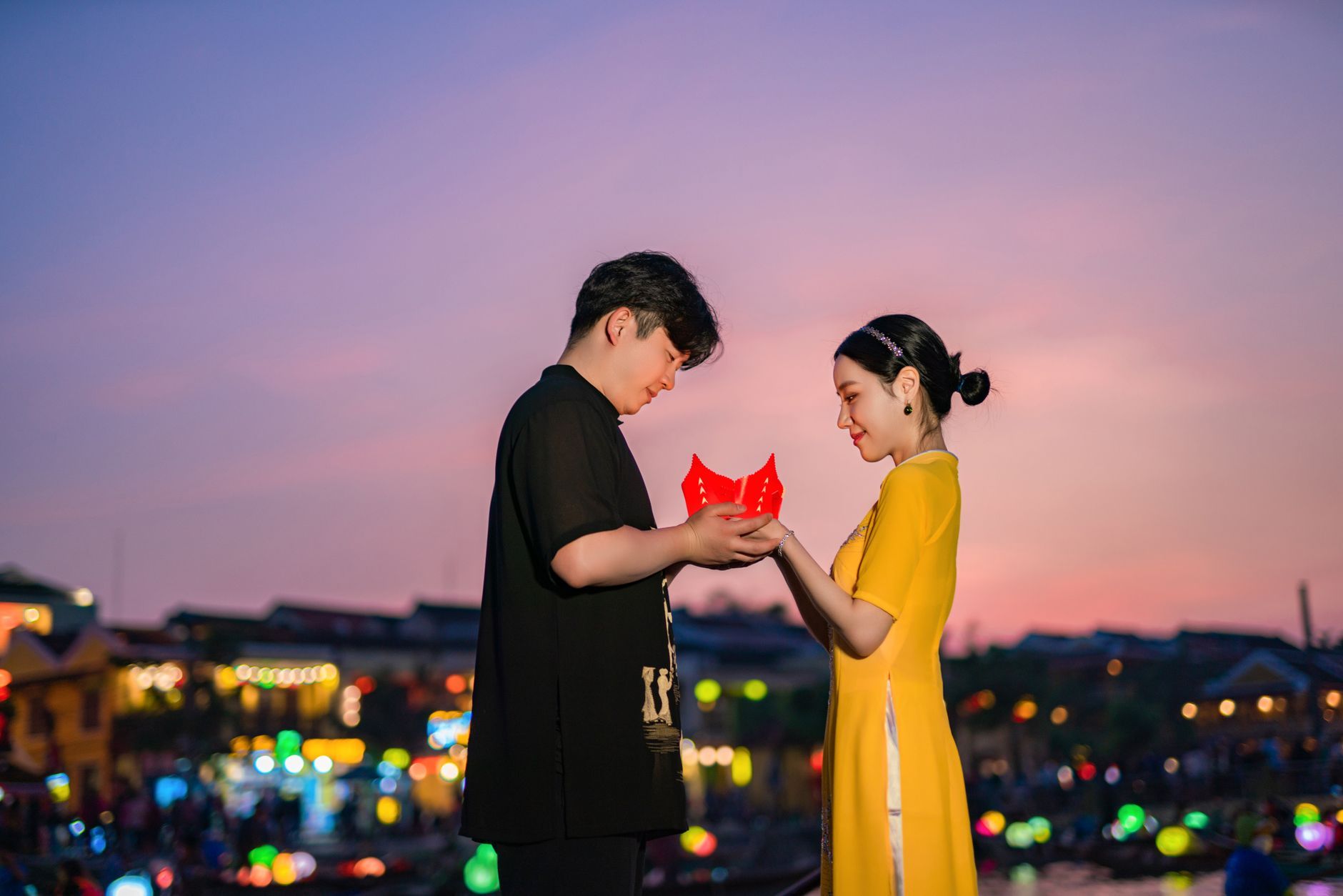 An Asian couple smiling together on a city street during sunset.