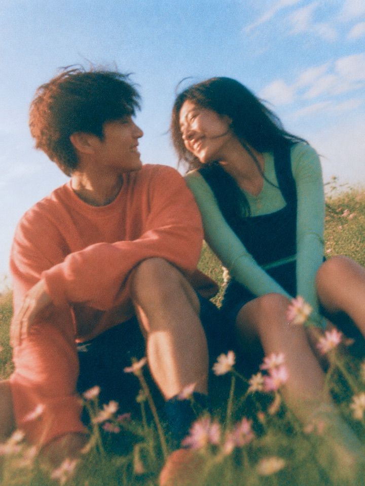 A couple sitting close together and laughing in a sunlit field