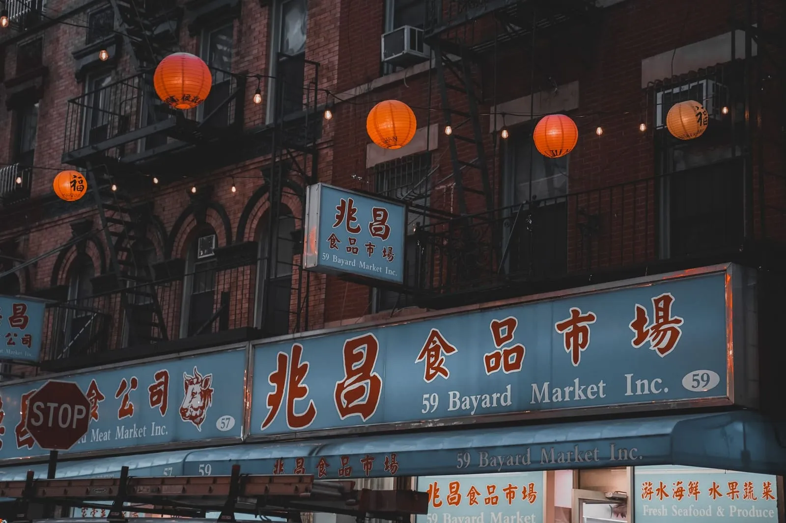 A rainy evening street in Manhattan’s Chinatown, glowing with neon signs.