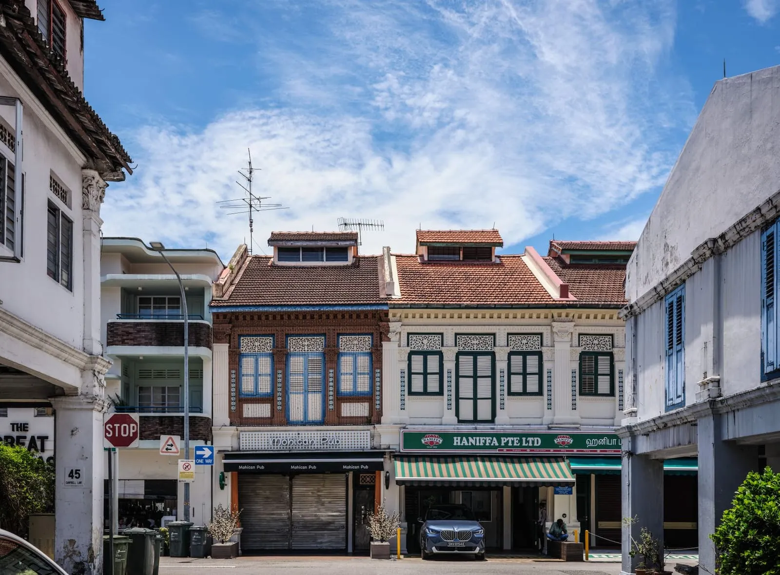 Colorful shophouses in Singapore's Chinatown under a bright sky.