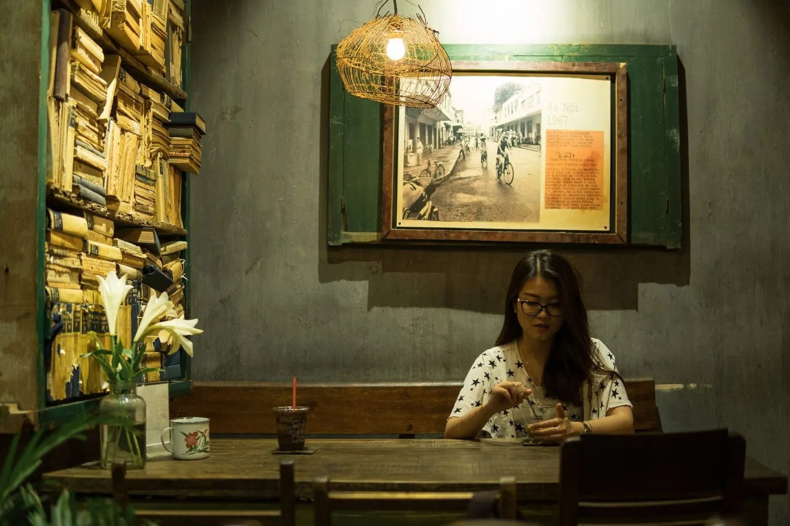 A cozy, sunlit café scene with two tea cups on a wooden table between books and flowers, suggesting conversation and connection.