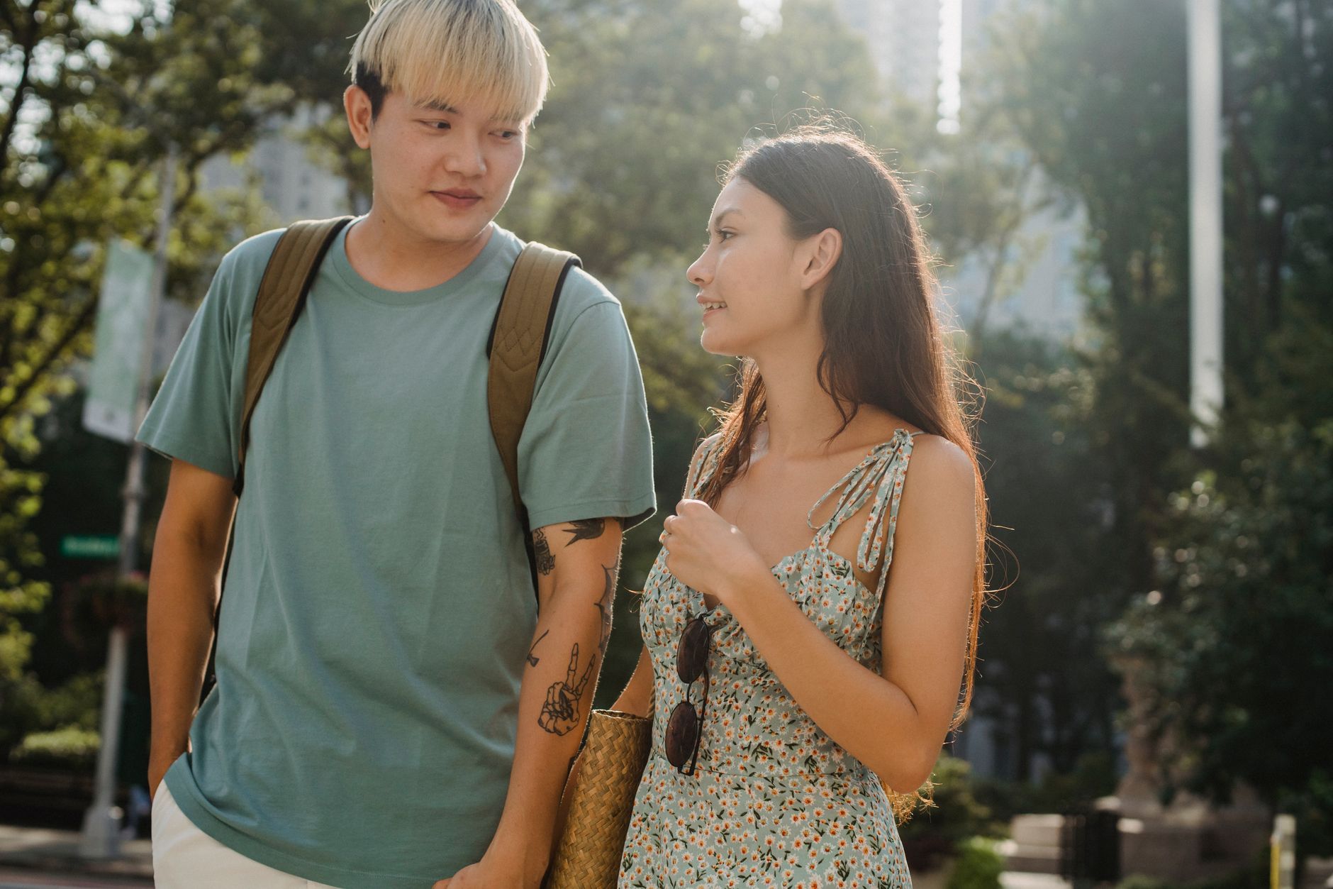 An Asian couple talking and laughing on a park bench during the day.