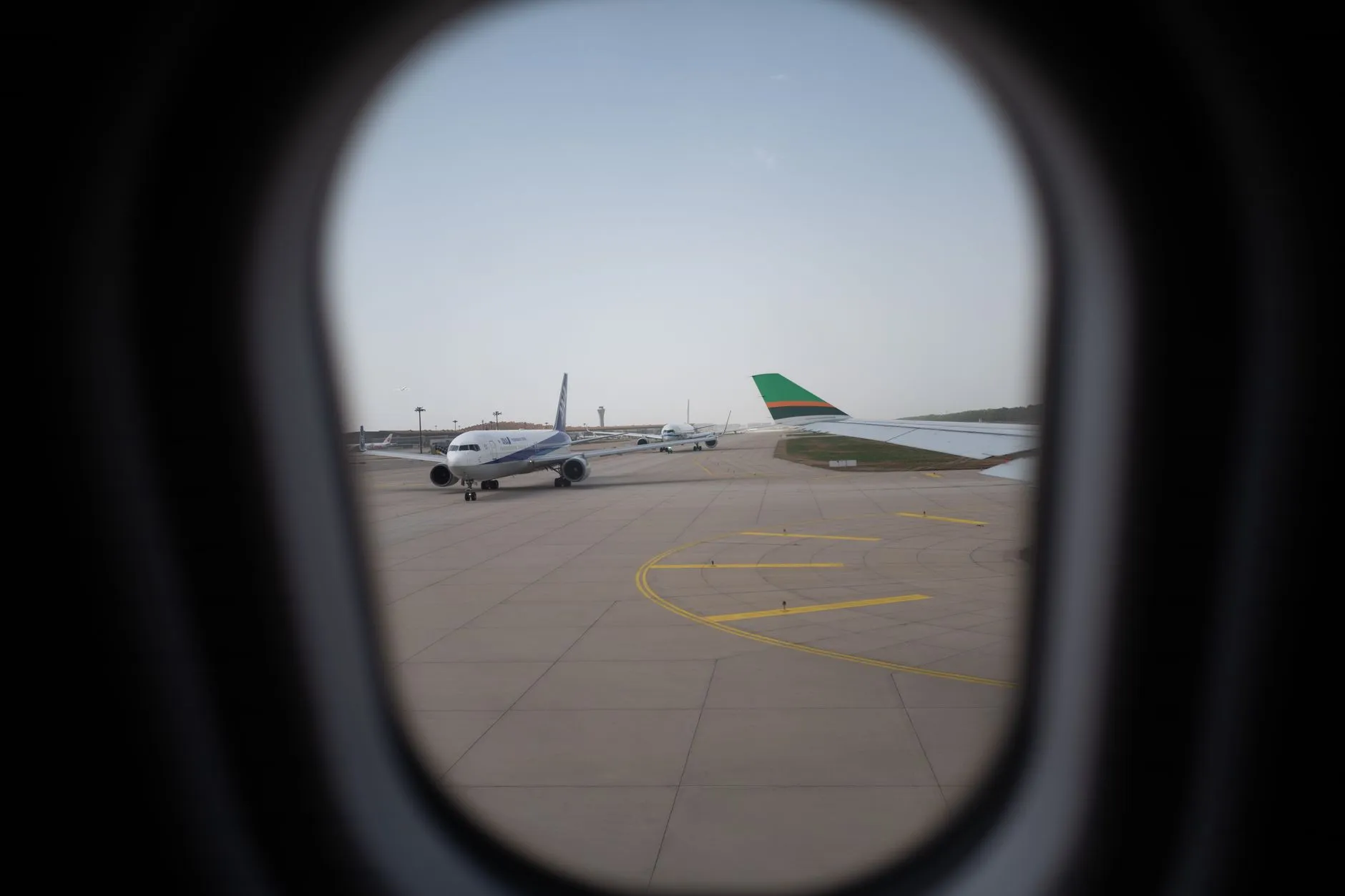 An airplane on an airport runway, seen through a cabin window.