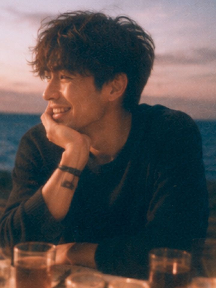 A man smiling at golden hour beside the sea