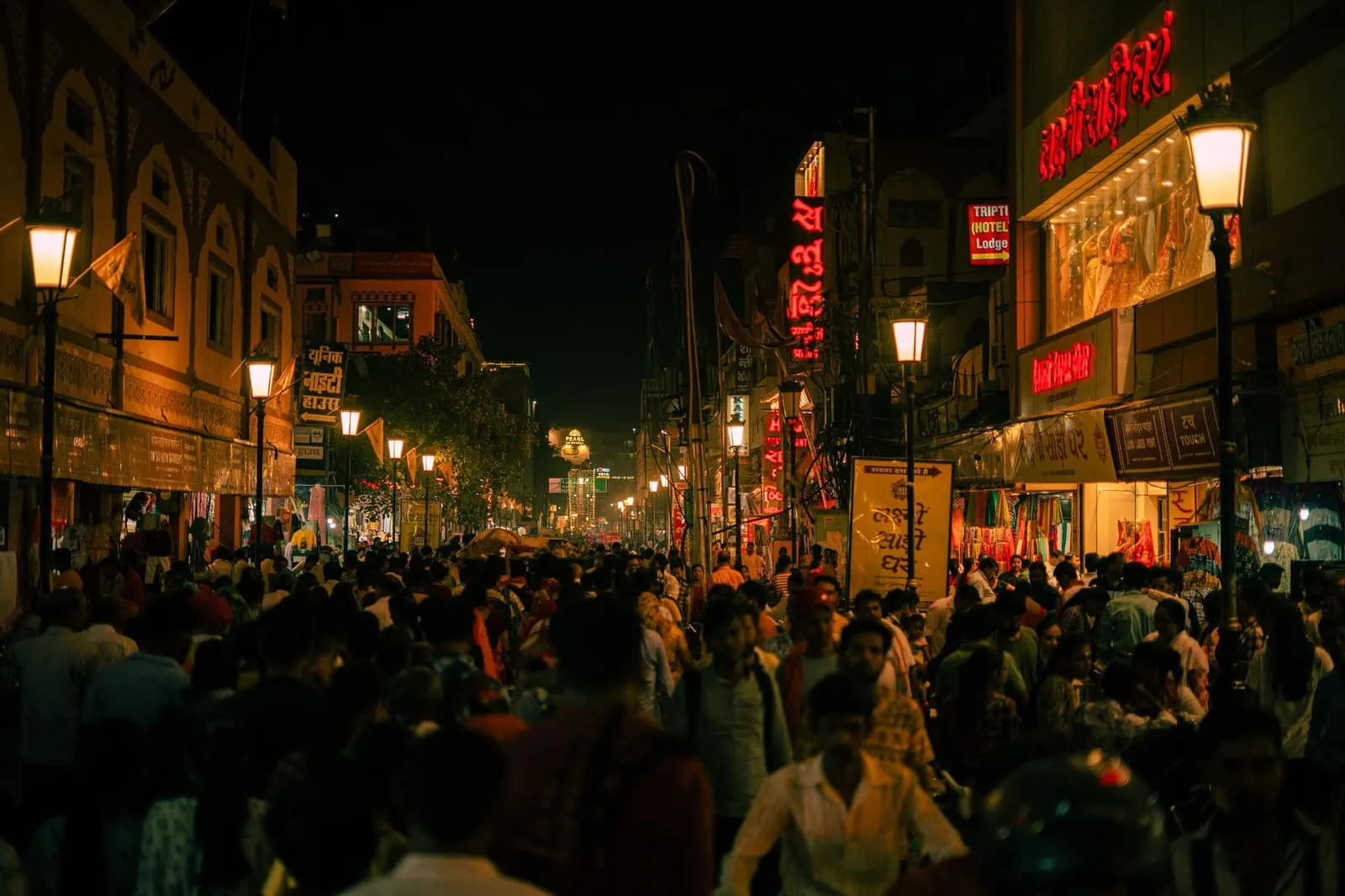 Colorful Indian city street scene with cafes and lights at dusk.