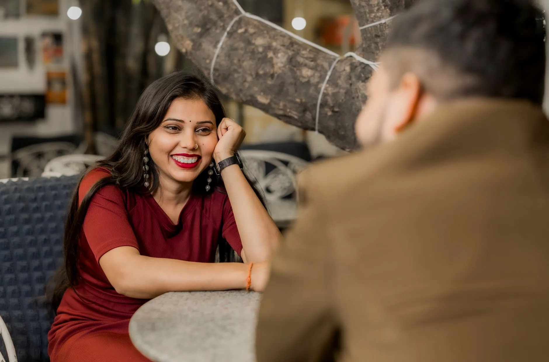 A South Asian couple smiling during an outdoor café conversation.